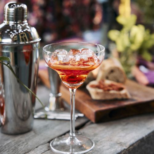 Cocktailglas met vulling  gepresenteerd in een sfeervolle omgeving.