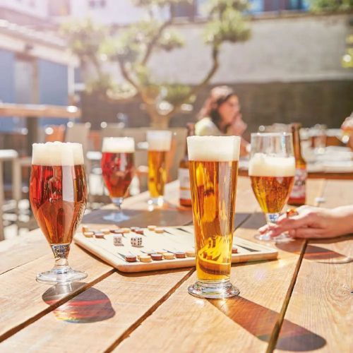 Gevuld Cervoise bierglas 50 cl. in gebruik, geplaatst in een natuurlijke drinksituatie.