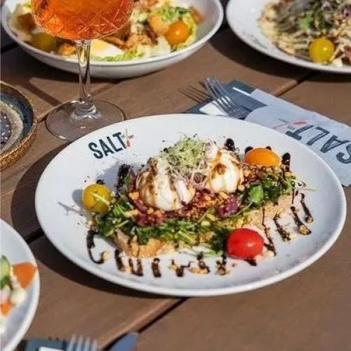 Sfeerbeeld van wit Hotel coupebord 25 cm met inhoud en zichtbaar logo in een realistische setting.