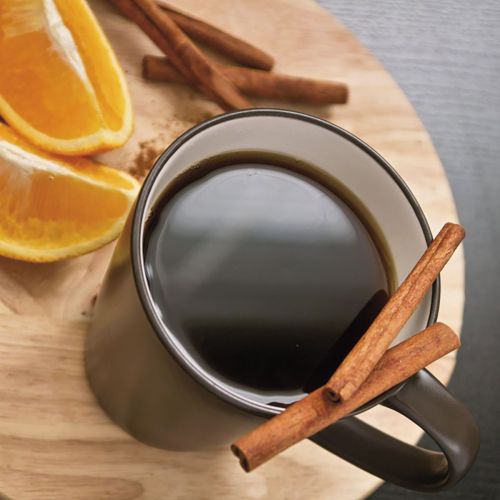 Zwart-witte porseleinen Delta mok 30 cl. met bedrukt logo, gevuld met warme drank in interieuromgeving.