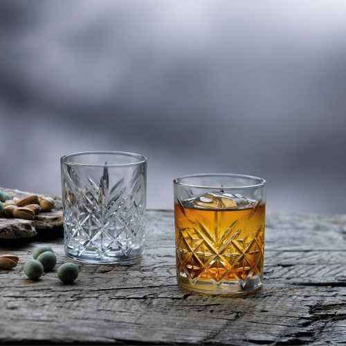 Timeless Whiskyglas met whisky op houten tafel in sfeervolle, warme omgeving.
